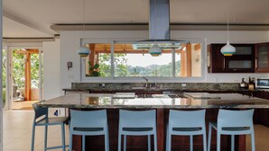 Una cocina moderna con una isla grande, taburetes de bar e iluminación colgante.
