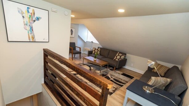 Een moderne woonkamer met een houten bank, een sofa, een salontafel en een schilderij aan de muur.