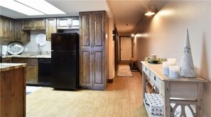 A kitchen with wooden cabinets, a black refrigerator, and a wooden dining table with candles. - 1BD PowderPointe Condo-Walk to Resort! (Park City)