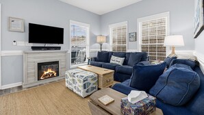 Ein Wohnzimmer mit Kamin, Fernseher, einem blauen Sofa und einem Deckenventilator.