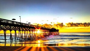 Eine Pier, die sich ins Wasser erstreckt, mit einem Sonnenuntergang im Hintergrund.