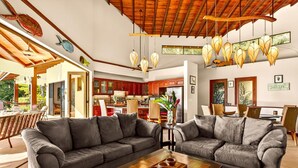 A spacious living area with a grey sectional sofa, a wooden coffee table, and a kitchen in the background.