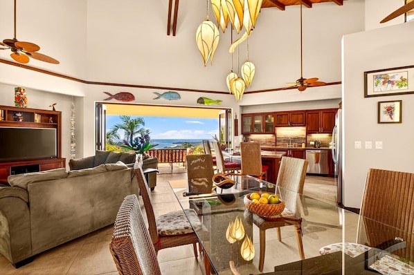 A spacious living area with a sofa, dining table, and chairs, a kitchen with wooden cabinets, and a view of the ocean. - Ocean view, Secret place - Casa Espectacular (Uvita)