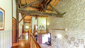 A spacious hallway with wooden floors and a stone wall on one side.