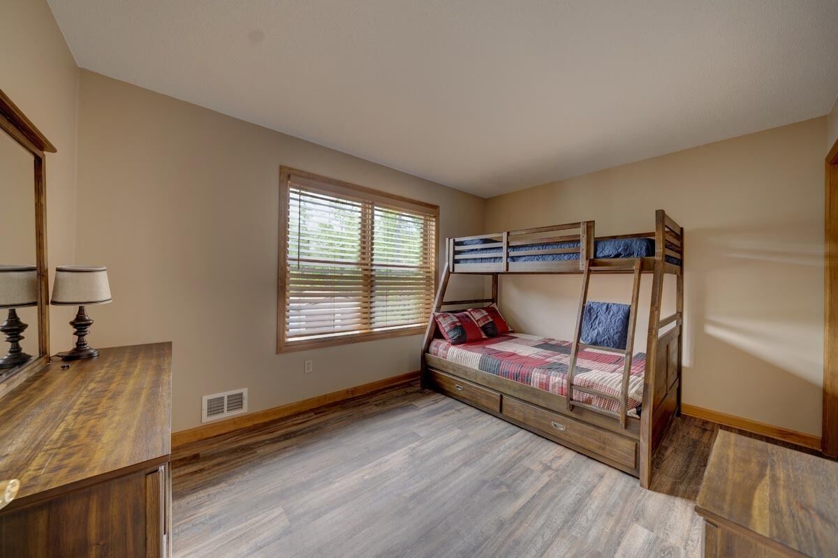 Une chambre avec un lit superposé, un bureau avec une lampe et une fenêtre avec des stores.
