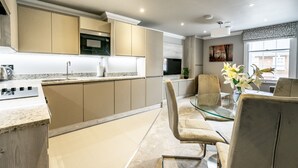 A modern kitchen with beige cabinets, a stainless steel range hood, and a glass dining table with chairs. - Bootham Urban Space -  a family break that sleeps 4 guests  in 2 bedrooms (York)