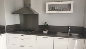 Une cuisine moderne avec des armoires blanches, une hotte en acier inoxydable, un évier encastré et une petite plante en pot.
