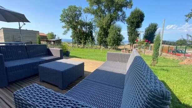 Une terrasse dotée de meubles en osier et offrant une vue sur le paysage environnant.