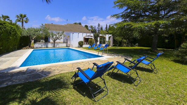 A swimming pool with blue chairs and a gazebo. - Villa  ADELFA (Salou)