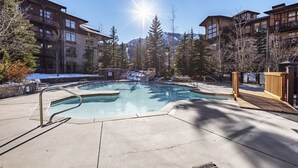 Un área de piscina con jacuzzi, rodeada de edificios y árboles.