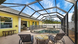 Eine überdachte Terrasse im Freien mit Pool, Sitzgelegenheiten und einer gelben Wand.