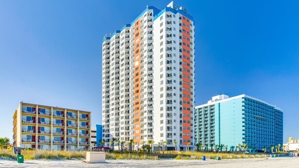 Un grand hôtel avec de nombreux étages, des balcons et une vue sur la plage.