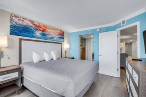A hotel room with a bed, bedside tables, a wardrobe, and a bathroom visible through an open door. - Grand Cayman by Escape (Myrtle Beach)