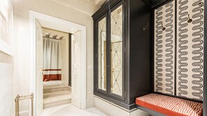 A hallway with a bench, a door with a striped curtain, and a patterned wall. - L'Opera Divina (Venice)