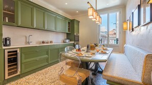 A modern kitchen with green cabinets, a dining table with chairs, and a sofa. - L'Opera Divina (Venice)