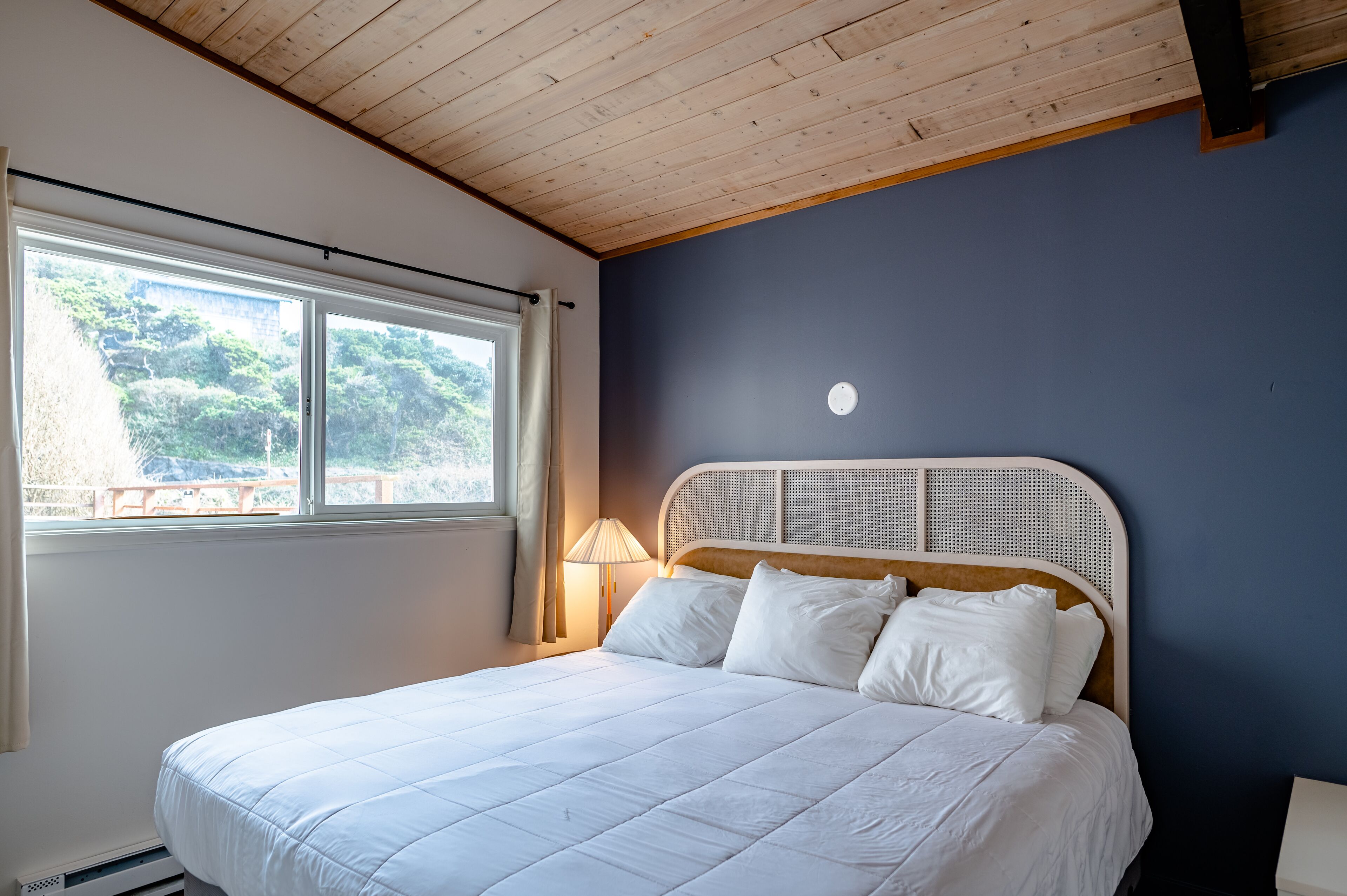 Een slaapkamer met een bed, een raam en een lamp.