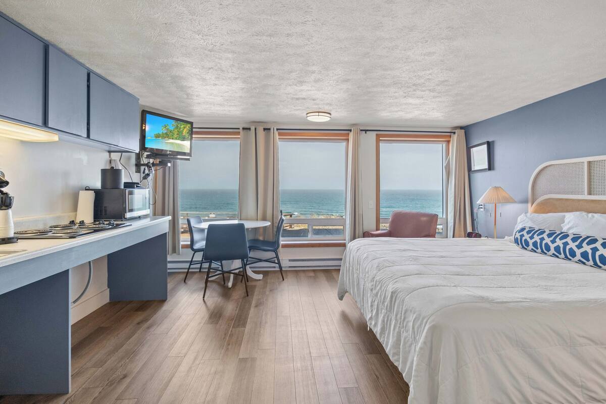 Een hotelkamer met een bed, een bureau met een computer, een stoel, een tafel en een televisie.