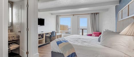 Une chambre d’hôtel équipée d’un lit, d’un bureau, d’une chaise, d’une télévision et d’un balcon avec vue.
