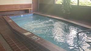 En inomhuspool med kakel på golvet och ett träpanelat tak.