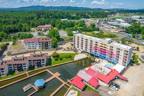 A multi-story hotel with balconies, a parking lot, and a river.