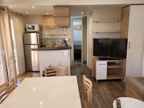 A compact living space with a kitchenette, a dining area, and a TV.