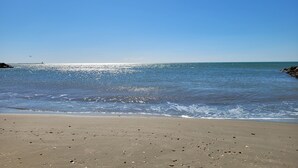 A beach with clear skies, calm water, and a distant lighthouse. - Vias Plage,la Carabasse Mobil Home Tout Confort (Vias-plage)