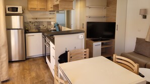 A compact kitchen with a microwave, refrigerator, and a flat-screen TV. - Vias Plage,la Carabasse Mobil Home Tout Confort (Vias-plage)
