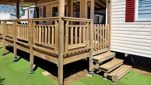 A wooden deck with a covered porch, steps leading to a door, and a small outdoor area with artificial grass. - Vias Plage,la Carabasse Mobil Home Tout Confort (Vias-plage)