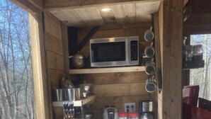 A compact kitchen with wooden cabinets, a microwave, and various kitchen utensils.
