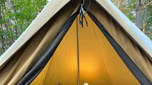 A tent with two beds, a lamp, and a small table.