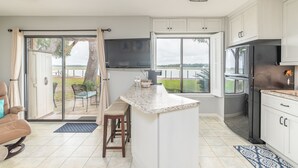 Une cuisine moderne dotée d’un grand îlot central, d’un téléviseur encastré et offrant une vue sur l’extérieur.