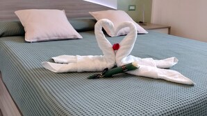 Een bed met een handdoek in de vorm van een hart, een groene deken en een wit kussen.