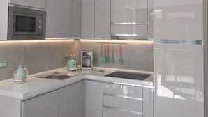 Een moderne keuken met grijze kastjes, een magnetron, een broodrooster en een koelkast.
