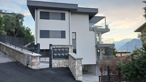 Een modern gebouw met twee verdiepingen, een stenen entree, een zwart hek en een balkon.