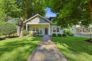 A residential house with a front porch, a pathway leading to the entrance, and a well-maintained lawn. - Modern CDA Retreat Walk to Lake and Hot Tub (Coeur d'Alene)