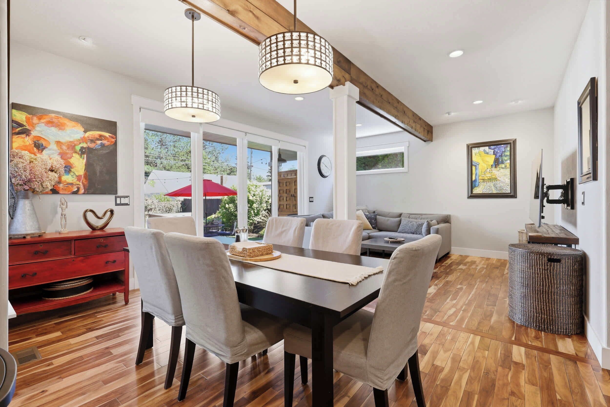 A dining area with a wooden table, chairs, and pendant lighting.