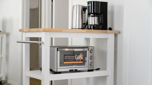 Un taulell de cuina amb un forn elèctric, un brollador d'aigua i una cafetera.