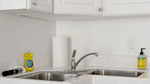 Una cuina amb dos vàters d'acer inoxidable, una ampolla de sabó per a plats, una ampolla de sabó de mans i un suport per a tovallons de paper.