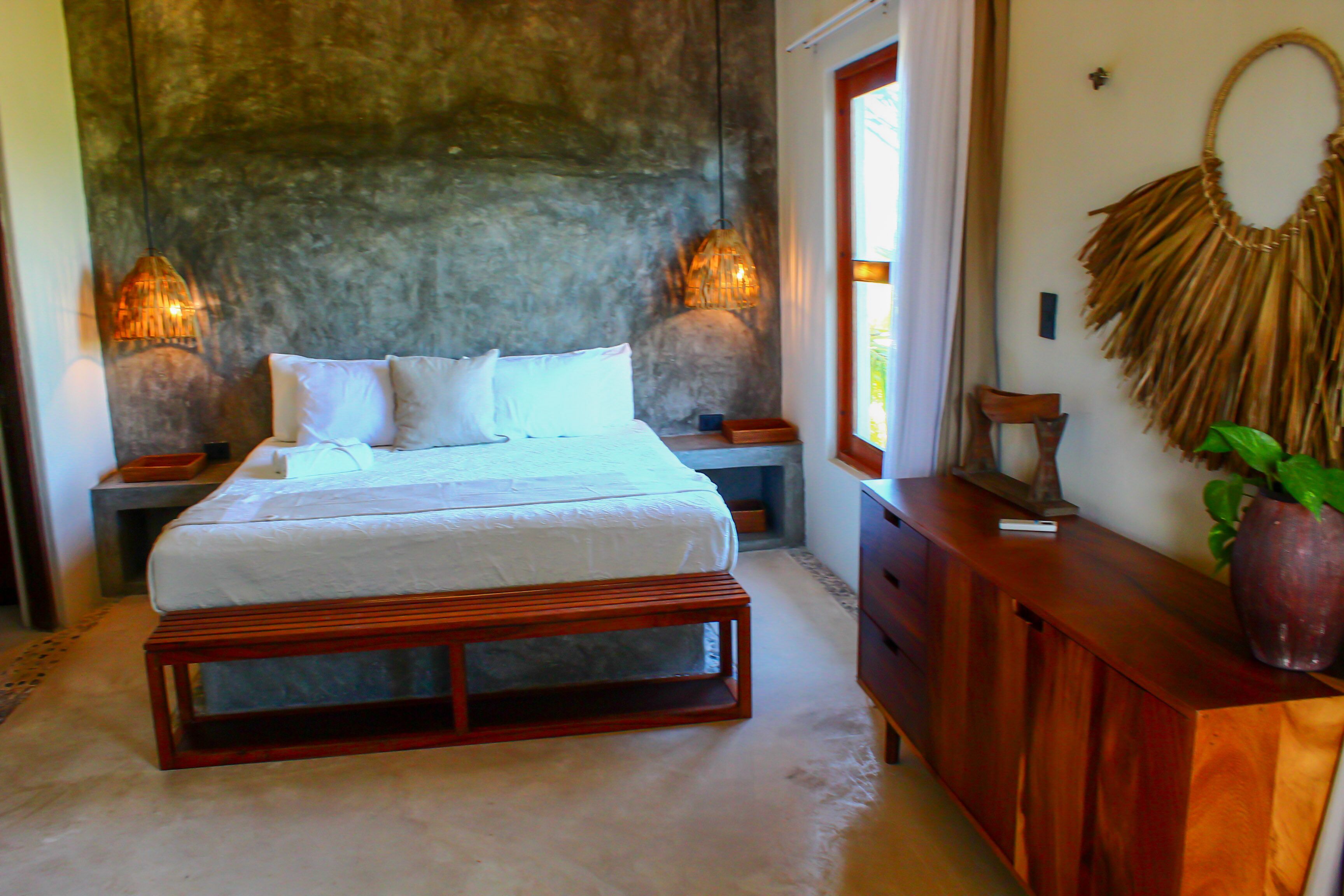 A bedroom with a bed, wooden nightstands, a dresser, and a wall-mounted decorative item.