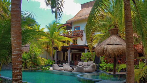 A pool area with lounge chairs and a thatched-roof structure. - Delos Luxury 9 Bedroom near Chicxulub (Progreso)