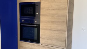 Una cocina con microondas y horno integrados, armarios de madera y una pared de acento azul.