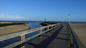A wooden boardwalk along a coastal area with a clear sky. - Studio Belle Vue Mer (Courseulles-sur-Mer)