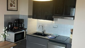 A modern kitchen with a built-in microwave, coffee maker, and sink. - Studio Belle Vue Mer (Courseulles-sur-Mer)