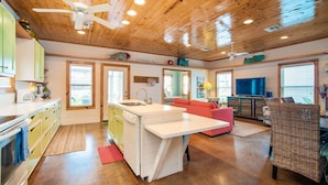 A spacious kitchen with a central island, wooden ceiling, and a dining area with a red sofa.