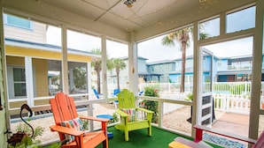 A covered outdoor seating area with two chairs, a bench, and a small table.