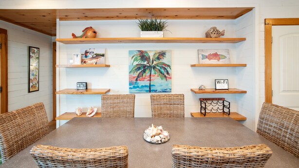 A dining area with a wooden table, wicker chairs, and a central decorative bowl.