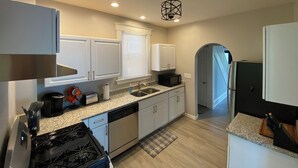 Una cocina moderna con armarios blancos, encimera de granito, lavavajillas integrado, estufa y microondas.