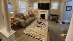 Una sala de estar con sofá, mesa de centro, chimenea y televisor.