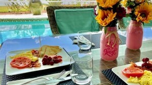 A dining table with breakfast plates, a glass of water, and two mason jars with flowers. - Located near downtown, restaurants and the beach ! (Naples)