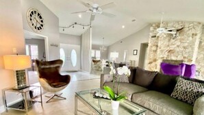 A modern living room with a glass coffee table, a leather armchair, and a sofa with patterned cushions. - Located near downtown, restaurants and the beach ! (Naples)